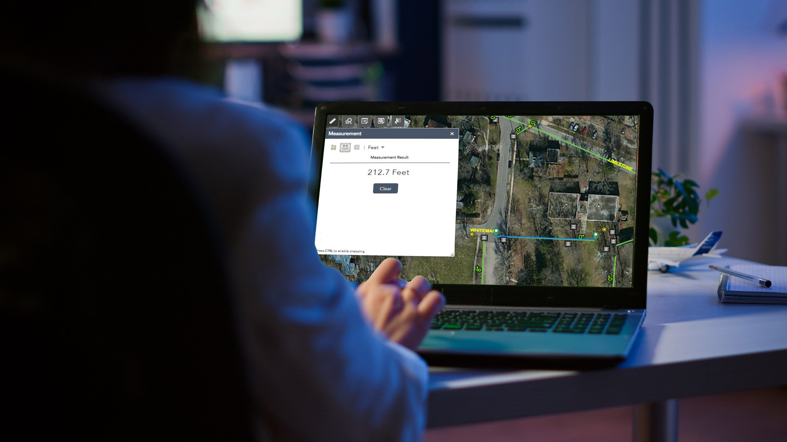 Close up of freelancer typing on laptop with green screen sitting at desk in start up office overworking. Manager watching desktop monitor display with green mockup, chroma key, during night time